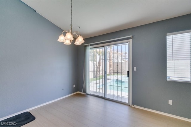 interior space with an inviting chandelier, hardwood / wood-style flooring, and vaulted ceiling