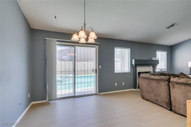 living room featuring an inviting chandelier, a tile fireplace, and light hardwood / wood-style floors