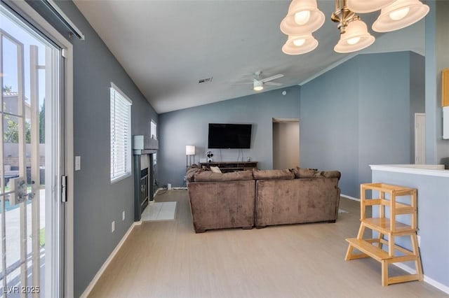 living room featuring lofted ceiling, ceiling fan with notable chandelier, and light wood-type flooring