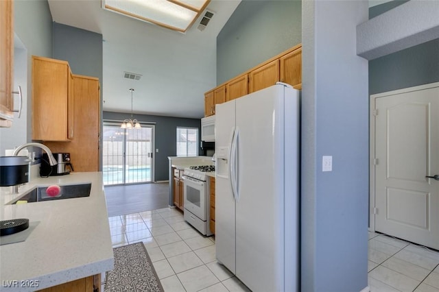 kitchen featuring light tile patterned flooring, white appliances, a chandelier, and sink