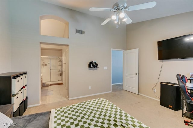 carpeted bedroom with connected bathroom, a towering ceiling, and ceiling fan