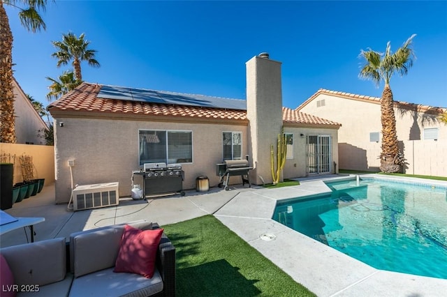 rear view of property featuring a fenced in pool, a patio area, and solar panels