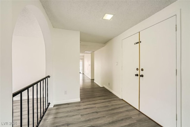 hall featuring dark wood-type flooring and a textured ceiling