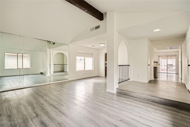 empty room with high vaulted ceiling, light wood-type flooring, a wealth of natural light, and beam ceiling