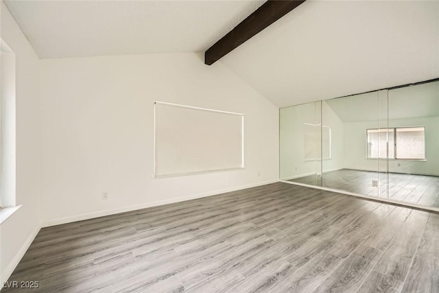 interior space featuring hardwood / wood-style floors and vaulted ceiling with beams