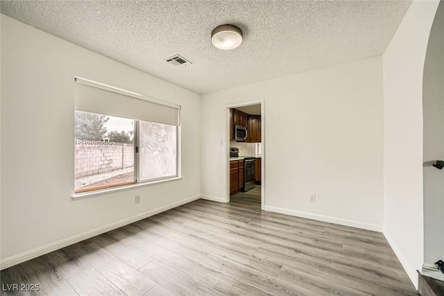 empty room with light hardwood / wood-style flooring and a textured ceiling