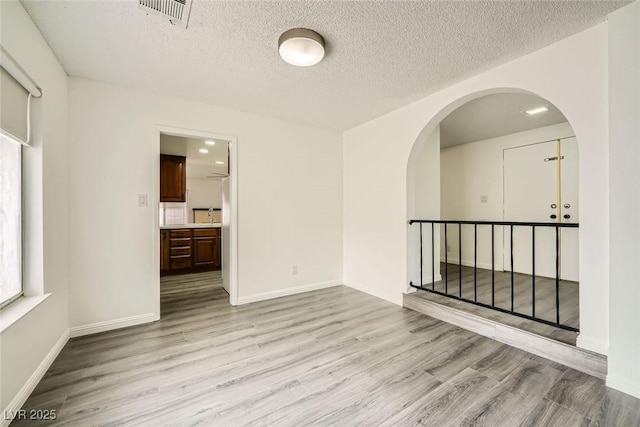 spare room with light hardwood / wood-style floors and a textured ceiling