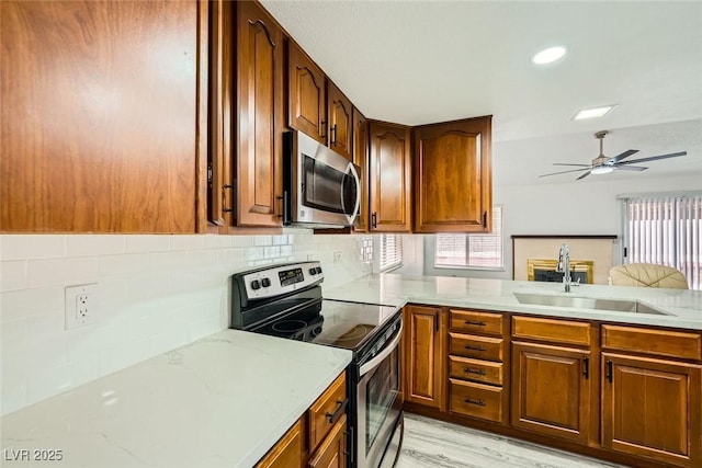 kitchen featuring tasteful backsplash, sink, ceiling fan, kitchen peninsula, and stainless steel appliances