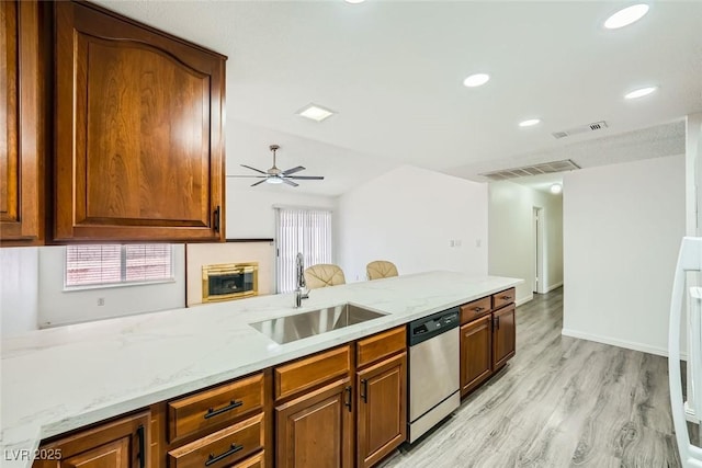 kitchen with sink, light wood-type flooring, dishwasher, ceiling fan, and light stone countertops