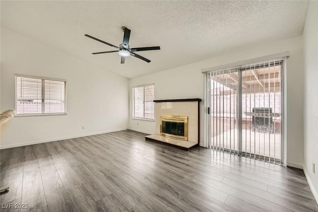 unfurnished living room featuring wood-type flooring, vaulted ceiling, ceiling fan, and a textured ceiling