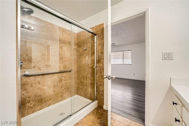 bathroom featuring walk in shower, vanity, tile patterned flooring, and a textured ceiling