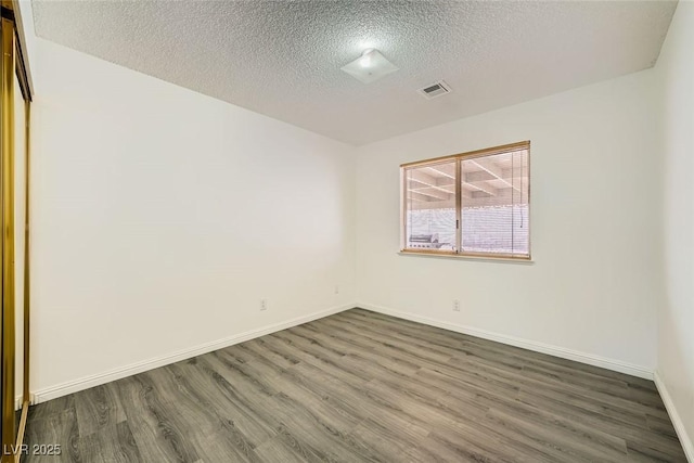 spare room with dark hardwood / wood-style flooring and a textured ceiling