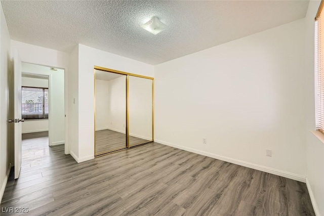 unfurnished bedroom featuring hardwood / wood-style flooring, a closet, and a textured ceiling