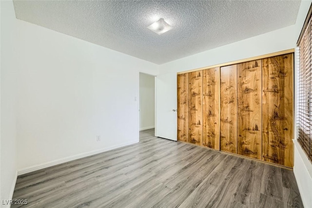 unfurnished bedroom with hardwood / wood-style flooring, a closet, and a textured ceiling