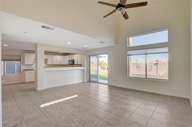 unfurnished living room featuring light tile patterned floors, a towering ceiling, and ceiling fan