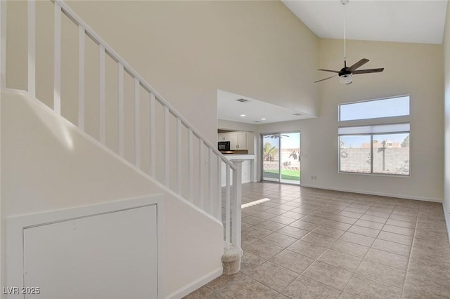 staircase featuring a high ceiling, tile patterned floors, and ceiling fan