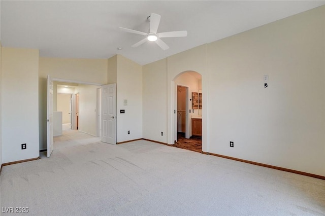 unfurnished bedroom featuring ceiling fan, light colored carpet, vaulted ceiling, and ensuite bath