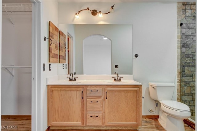 bathroom featuring vanity, wood-type flooring, toilet, and a shower with shower door