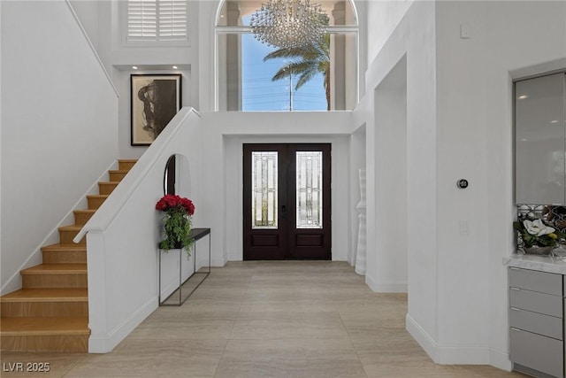 entrance foyer with a notable chandelier, french doors, and a high ceiling