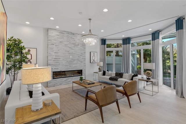 living room with light hardwood / wood-style flooring, a notable chandelier, and a fireplace