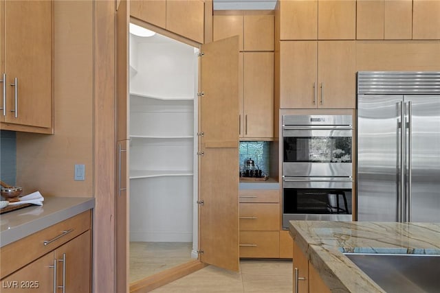 kitchen with light brown cabinetry, backsplash, light tile patterned flooring, and appliances with stainless steel finishes