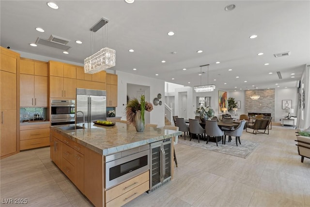 kitchen with pendant lighting, a large island, built in appliances, and beverage cooler