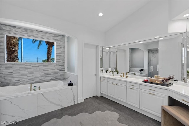 bathroom with vanity, vaulted ceiling, and independent shower and bath