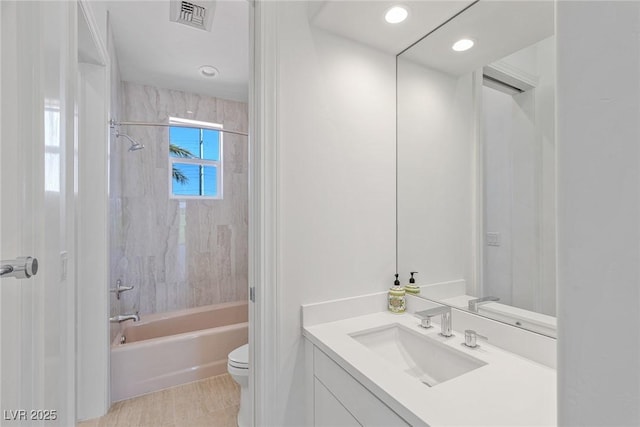 full bathroom featuring tiled shower / bath, vanity, and toilet