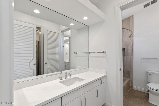 full bathroom with tiled shower / bath, vanity, and toilet