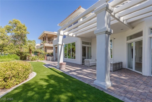 back of property with a pergola, a lawn, and a patio area