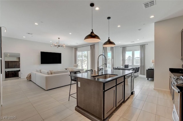 kitchen with sink, decorative light fixtures, an island with sink, and appliances with stainless steel finishes