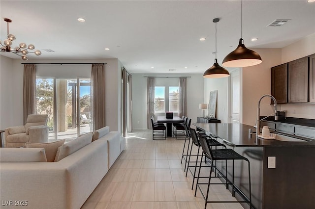 interior space featuring sink, light tile patterned floors, a breakfast bar, dark brown cabinetry, and decorative light fixtures