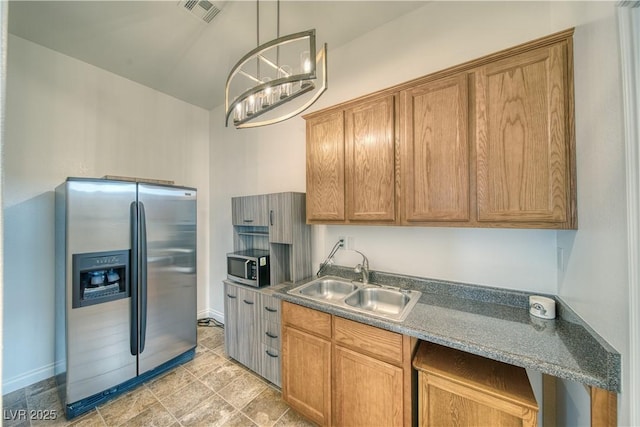 kitchen featuring appliances with stainless steel finishes, sink, pendant lighting, and an inviting chandelier