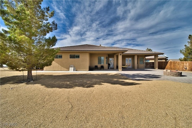 back of property with a fire pit and a patio