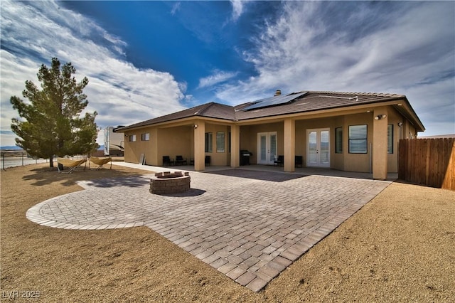 back of house featuring a patio, a fire pit, french doors, and solar panels