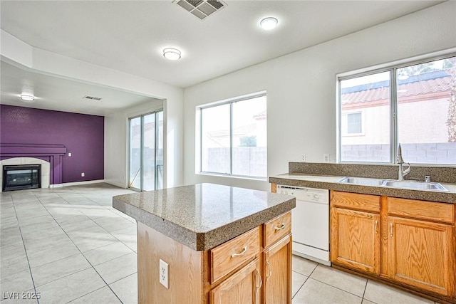 kitchen with dishwasher, a kitchen island, sink, and light tile patterned floors