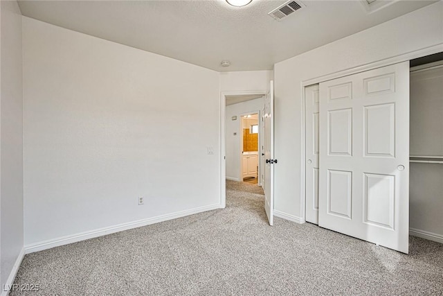 unfurnished bedroom featuring light colored carpet, a closet, and a textured ceiling