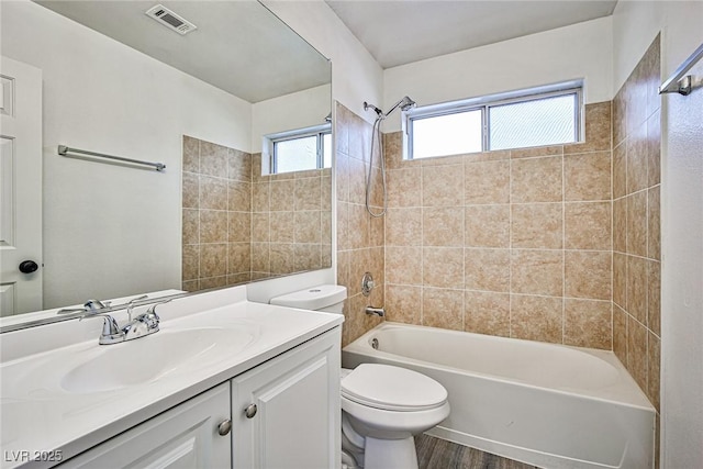 full bathroom with vanity, toilet, tiled shower / bath combo, and hardwood / wood-style floors