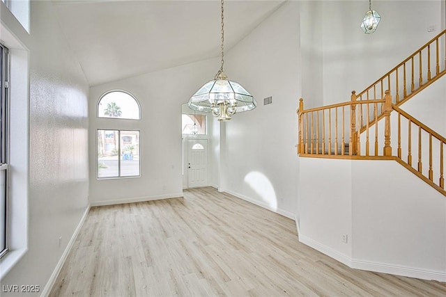 interior space featuring light wood-type flooring, an inviting chandelier, and high vaulted ceiling