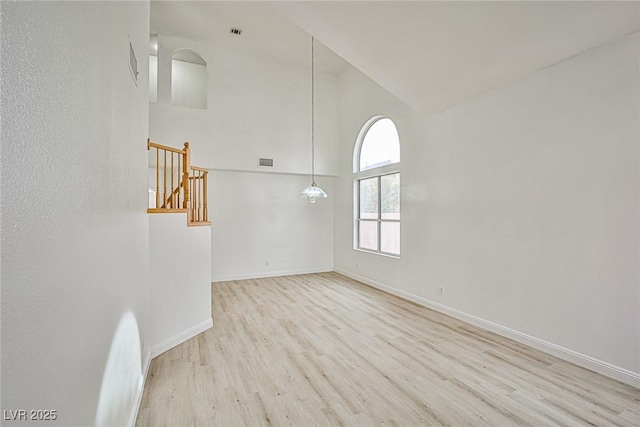 spare room featuring a high ceiling and light hardwood / wood-style floors