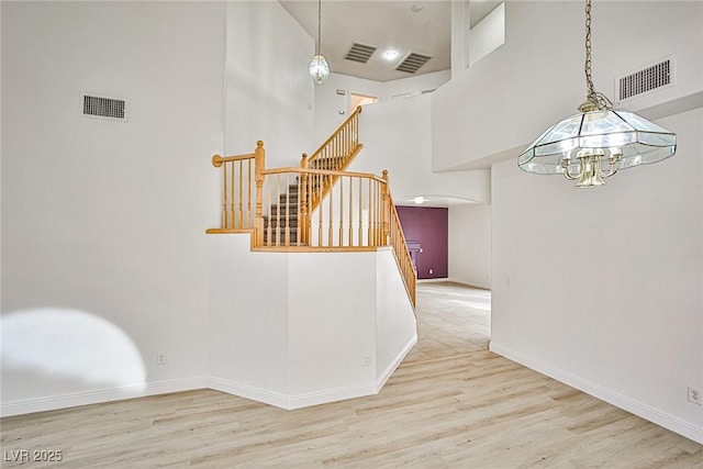 staircase featuring hardwood / wood-style flooring, a towering ceiling, and a chandelier