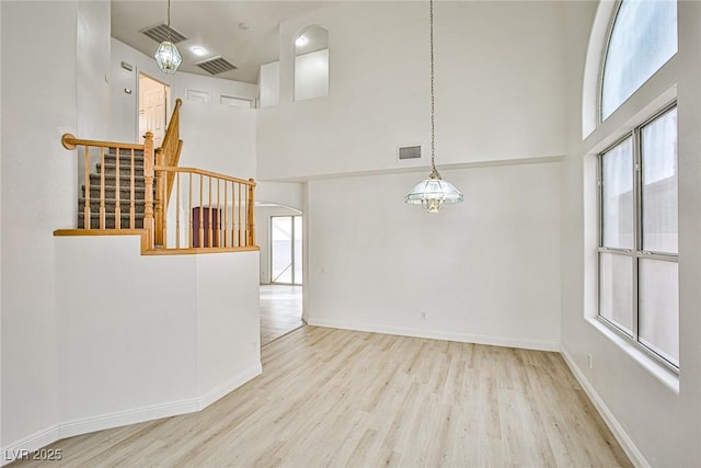 empty room with a high ceiling and light hardwood / wood-style floors