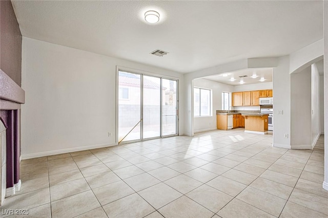 unfurnished living room featuring light tile patterned flooring and sink