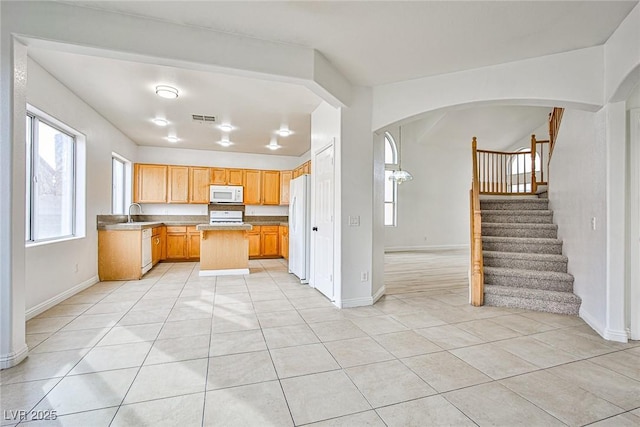 kitchen with light tile patterned flooring, white appliances, and sink