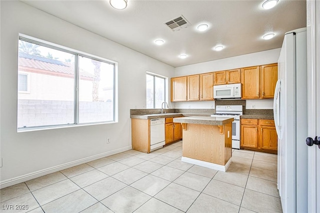 kitchen with a kitchen island, sink, light tile patterned floors, and white appliances