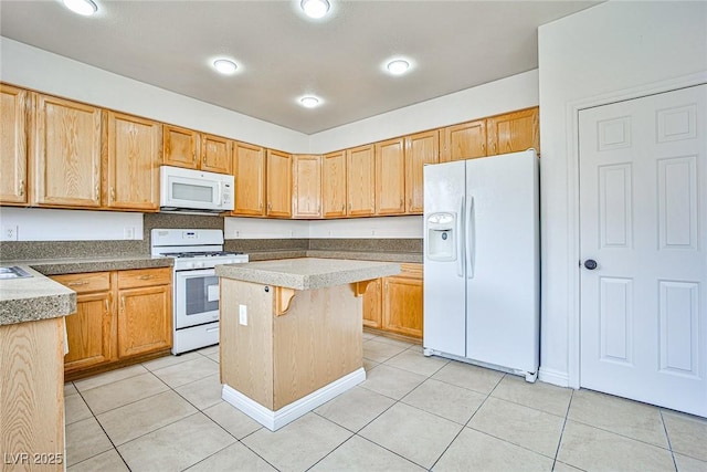 kitchen featuring light tile patterned flooring, white appliances, a kitchen bar, and a center island