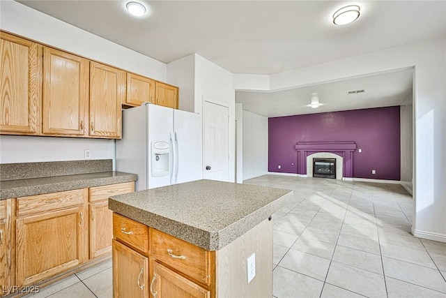 kitchen featuring light tile patterned floors, white refrigerator with ice dispenser, and a center island