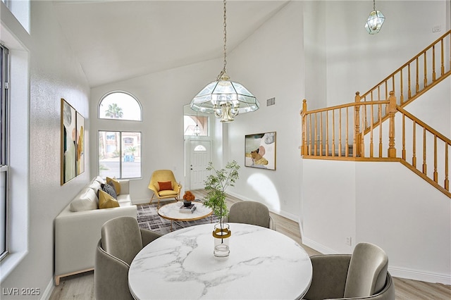 dining room with a chandelier, high vaulted ceiling, and light wood-type flooring