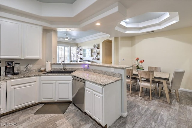 kitchen featuring sink, white cabinetry, a raised ceiling, stainless steel dishwasher, and kitchen peninsula