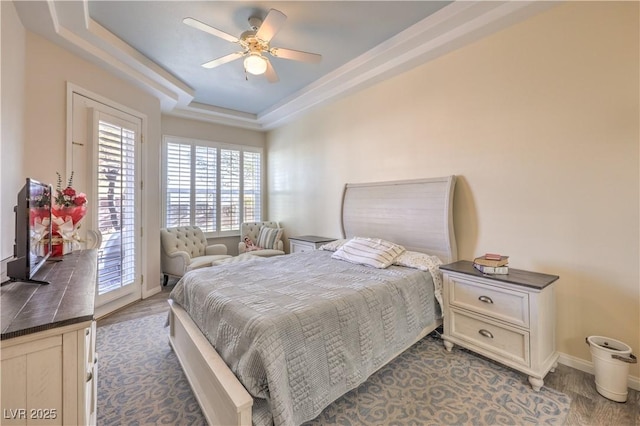 bedroom featuring access to exterior, ceiling fan, and a tray ceiling